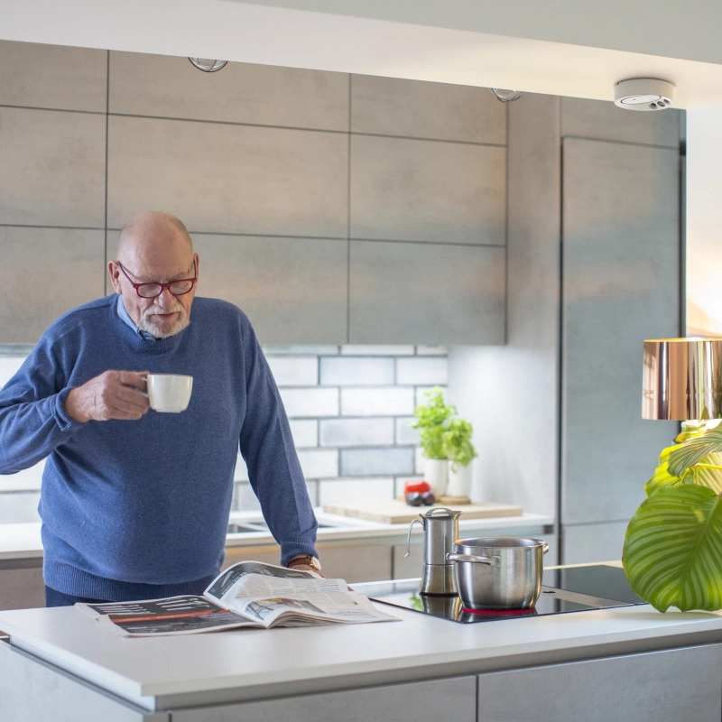 Elderly man cooking under a ceiling-mounted Airis-C stove guard