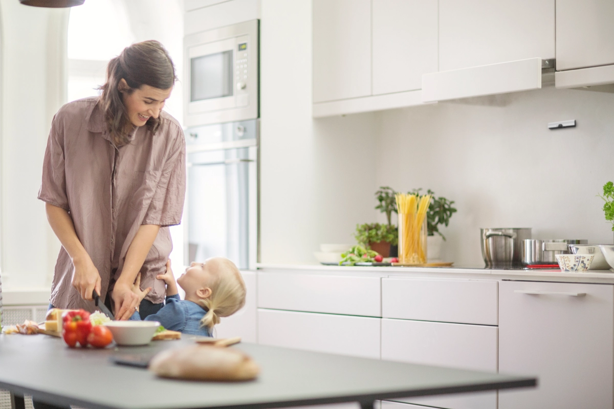 Mother and young daughter preparing food with Airis stove guard protecting the electric hob