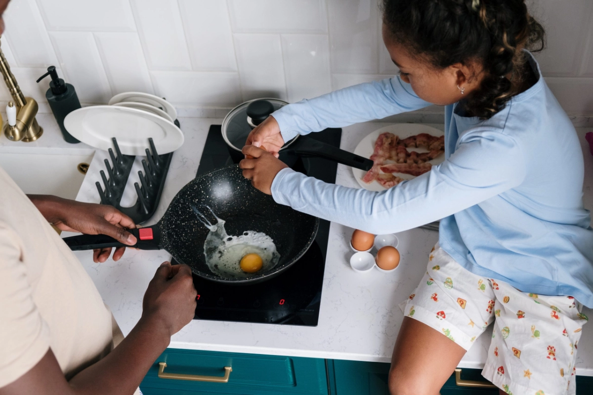 Photo by cottonbro from Pexels - a girl helps her father cook eggs on the kitchen stove